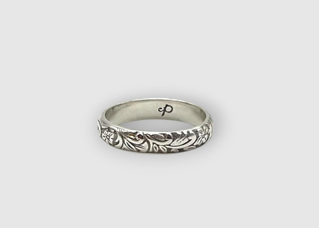 Silver ring with intricate design on a light gray background