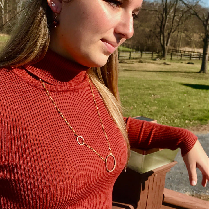 circles necklace in gold on model with green grass