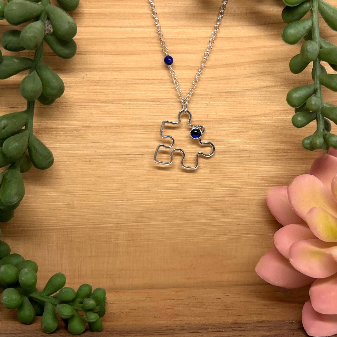 Autism Awareness Necklace Puzzle Piece 2 on wood background