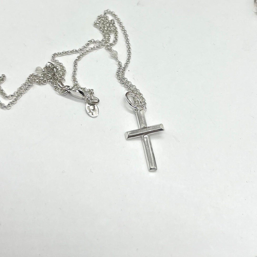 Silver cross necklace on a white background