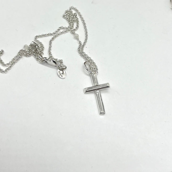 Silver cross necklace on a white background