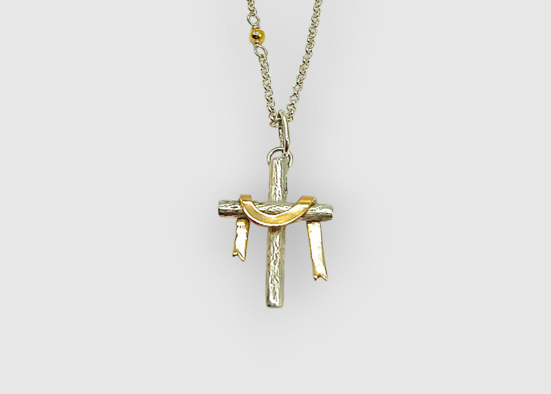 Gold and silver cross pendant on a chain against a white background