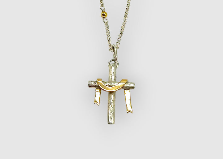 Gold and silver cross pendant on a chain against a white background