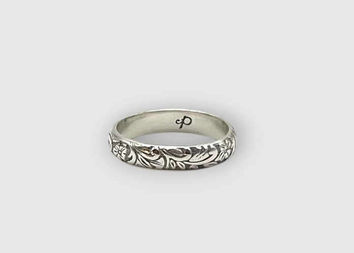 Silver ring with intricate design on a light gray background